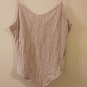 Ljuslila stringbody från H&M - Ljuslila stringbody från H&M med tunna axelband och ribbad struktur. Materialet är 86% viskos. Oanvänd. 