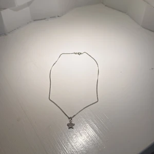 Silverhalsband med stjärnhänge - Ett stilrent halsband i silverfärg med ett litet stjärnformat hänge. Hänget har små glittrande detaljer som ger extra shine. Perfekt för dig som gillar enkla men snygga smycken med en touch av glitter.