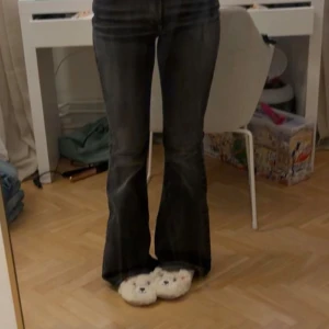 Svarta bootcut jeans - Säljer ett par svarta bootcut jeans med snyggt utsvängda ben. Jeansen har klassisk femficksdesign och är i ett stretchigt denimtyg som sitter tajt upptill och släpper ut vid vaden. Perfekta för dig som gillar en retro vibe och vill ha en cool siluett.