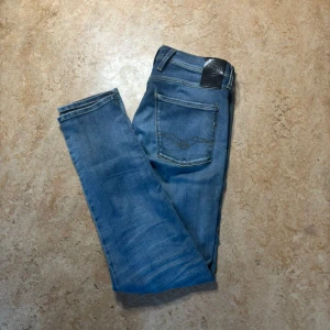 Replay Anbass jeans blå 31/34 - Snygga blå jeans från Replay, modell Anbass. Klassisk femficksdesign med ljus tvätt och raka ben. Jeansen har normal passform och är tillverkade i slitstarkt bomullsmaterial. Perfekt för dig som gillar stilrena och bekväma jeans.