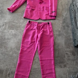 Rosa kostym från Suitmeister, stl S - Säljer en riktigt snygg rosa kostym från Suitmeister i storlek S. Setet består av en klassisk kavaj med två knappar och matchande byxor med raka ben. Kostymen är helfärgad och har en cool, färgstark look som verkligen sticker ut.