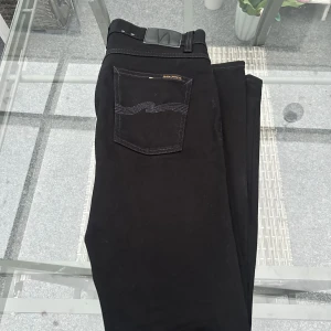 🖤 Nudie Jeans Lean Dean – Dry Everblack W33 L32 🖤 - Riktigt snygga svarta Nudie Jeans Lean Dean i modellen Dry Everblack. Slim fit med lite stretch, sitter grymt bra och håller formen. Gjorda i 99 % ekologisk bomull och 1 % elastan, så både bekväma och hållbara. Färgen är djupt svart och håller sig fin länge.  🖤 Storlek: W33 L32 🖤 Modell: Lean Dean 🖤 Färg: Dry Everblack 🖤 Passform: Slim fit / stretch 🖤 Material: Ekologisk bomull, elastan 🖤 Skick: Mycket bra – sparsamt använda  