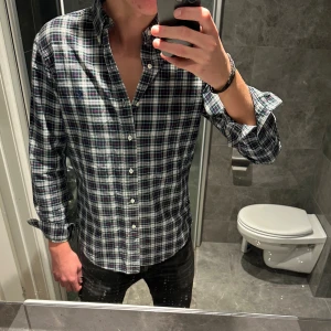 Rutig skjorta från Ralph Lauren - Snygg rutig skjorta från Ralph Lauren i mörkblått, grönt och vitt med diskret logga på bröstet. Riktigt bra skick. Jag är 188cm och bär storlek M på bilden. Hör av er vid funderingar:)