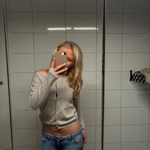 Grå kofta med pärlor och knappar - Superfin grå kofta med glittrande pärlor över hela tröjan. Den har knappar framtill, lång ärm och en lite croppad passform. Koftan är använd fåtal gånger och jag har även sytt in den lite i midjan. Har inte klippt bort de tyget så antingen om man gör de själv eller om man vill ha den lite större så sprättar man bara upp tråden eller om du vill att jag gör de. Priset går att diskutera. Vid frågor tveka inte att skriva💕