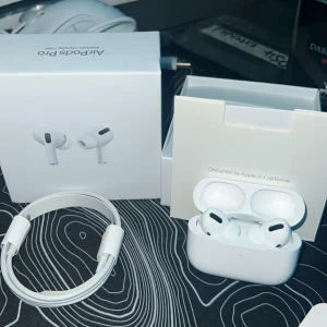 AirPods Pro - Säljer ett par AirPods Pro i mycket fint skick, komplett med originalkartong, laddningskabel och extra öronkuddar. Hörlurarna är trådlösa och har aktiv brusreducering. Inga synliga repor eller skador, allt fungerar som det ska. Perfekt för musik, samtal och träning.