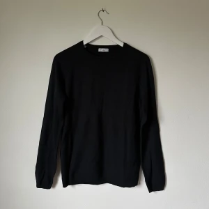 Mörkblå stickad tröja Selected Homme - Mörkblå stickad tröja från Selected Homme Identity i storlek L. Tröjan har rund hals, ribbade muddar och är tillverkad i en mix av bomull och akryl. Klassisk och enkel design med långärmade ärmar, perfekt för dig som gillar stilrena plagg. 4B2