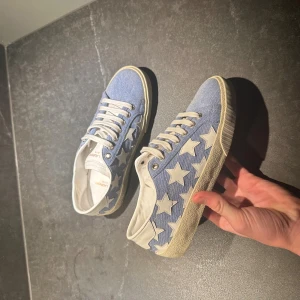 Blå sneakers från saint Laurent med vita stjärnor  - Hejsan! Jag säljer nu dessa riktigt feta skor ifrån saint Laurent i storlek 35-36! Dem är i väldigt bra skick och har noll defekter. Självklart äkta men har tyvär ingen box eller liknande. Hör av er om ni har frågor!