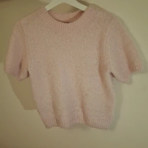 Ljusrosa stickad tröja Gina Tricot - Supermysig ljusrosa stickad t-shirt från Gina Tricot i storlek S. Tröjan har korta ärmar, rund hals och ribbade muddar vid hals och nederkant. 