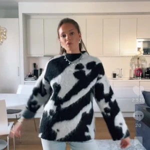 Zebramönstrad fluffig stickad tröja - Säljer en supermjuk och oversized stickad tröja från MQ med svartvitt zebramönster. Tröjan har lång ärm, rund hals och är gjord i en fluffig ullmix som ger en cool och trendig look.