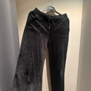 Svarta Juicy Couture S - Säljer ett par svarta mjukisbyxor från Juicy Couture i storlek S. Byxorna har bred resår i midjan med snörning där ett snöre saknar den silvriga metallen, uppsydda några centimeter men enkelt att sprätta upp 