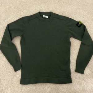 Stone Island junior grön stickad tröja - Mörkgrön stickad tröja från Stone Island Junior. Såklart äkta och mycket fint skick, bara ett pyttelitet hål i vänstra armhålan. Storlek 12/156 men liten i storleken. Pris går att diskutera vid snabb affär!