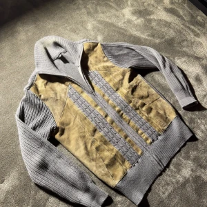 Brun och grå mocka-stickad cardigan - Snygg cardigan med brun mocka framtill och grå stickade partier på ärmar, sidor och krage. Jackan har dragkedja, ribbade muddar och kabelstickade detaljer längs framsidan. Perfekt för dig som gillar en unik och chill stil.