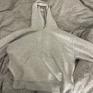 Ljusgrå hoodie med huva gina tricot xs - En stilren ljusgrå hoodie med klassisk huva och magficka. Tröjan har ribbade muddar vid ärmslut och nederkant, perfekt för en avslappnad och chill look. Passar dig som gillar enkel och clean streetstyle.