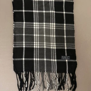 Svartvit rutig halsduk från Burberrys - Snygg halsduk från Burberrys i klassiskt svartvitt rutigt mönster med fransar i ändarna. Gjord i 100% lammull som känns mjuk och skön mot huden. Perfekt accessoar för att lyfta din outfit med en tidlös vibe. halsduken skickad från Norge och moms kan tilkomma. betalning måste ske via paypal eller liknande