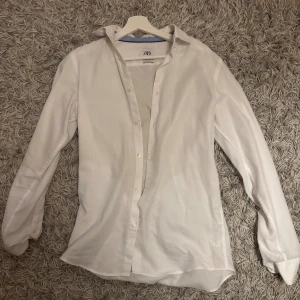 Vit slim fit skjorta från Zara - Vit skjorta från Zara i slim fit-modell med klassisk krage och knappar framtill. Skjortan har lång ärm och är tillverkad i mjukt bomullstyg som känns skönt mot huden. Perfekt för dig som gillar en clean och stilren look.