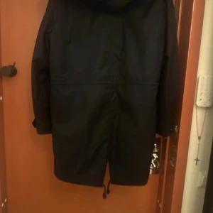Marinblå mörk parkas med päls från Mackage - Svart parkas från Mackage med fluffig päls på insidan och huvan. Jackan har långa ärmar, snörning nedtill och dragkedja framtill. Snygg och varm design med stilren look, perfekt för kalla dagar. Pälsen ger extra lyxig känsla och jackan har en loose passform.
