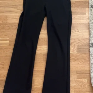 Svarta kostymbyxor från Lindex, 158 - Snygga svarta kostymbyxor från Lindex i storlek 158. Byxorna har klassisk rak passform med bootcut och diskreta fickor bak. Perfekt för dig som gillar stilrena och tidlösa plagg. Materialet är mjukt och bekvämt. Använt ca 10 gånger