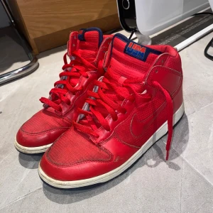 Nike dunk high USA 2012 - As feta Röda Nike dunk skor i storlek 42,5. Skorna kommer inte med Skolådan. Skorna är i bra skick men de har några små skavanker(kan skicka i dm) pris kan diskuteras vid snabb affär.