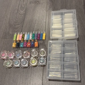 Nageldekorationer och glitter i olika färger - Säljer ett litet kit med nageldekorationer, glitter i burkar och små flaskor i regnbågens alla färger. Inkluderar även två askar med lösnaglar i olika storlekar. Allt för 150kr