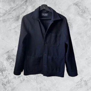 Mörkblå overshirt från A Day's March - Snygg mörkblå overshirt från A Day's March i klassisk design med tre stora fickor framtill och knappar hela vägen. Perfekt att slänga på över en t-shirt för en chill och stilren look. Materialet är mjukt och känns riktigt skönt mot huden.