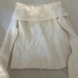 Vit offshoulder stickad tröja Gina Tricot - Superfin vit stickad tröja från Gina Tricot med bred ribbad offshoulder-krage. Tröjan har lång ärm och är perfekt för dig som gillar en stilren och mysig look. Passar till allt och är lätt att matcha med jeans eller kjol.