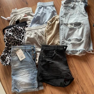 Mix av shorts i olika stilar och färger - Säljer ett gäng shorts: ljusblå randiga, beige linne, grå bomull, Adidas sportshorts, leopardmönstrade, ljusblå jeans med knappar, svarta jeansshorts med rå kant och slitningar samt ljusblå jeansshorts med stora hål. Perfekt för dig som gillar att variera din stil! 8 par kortbyxor i varierande storlekar såsom L, M, 40, 34. Ett par jeanskortbyxor är nya med lappen kvar, dom är storlek 40. Köpare står för frakt. Vill man ha separata bilder är det bara att höra av sig.