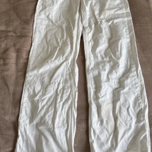 Vita raka jeans från Kappahl  - Säljer ett par vita jeans från Kappahl i rak modell. Byxorna har klassisk femficksdesign, silverfärgade nitar och knapp, samt normal midja. Materialet är kraftigt denim i bomull som ger en clean och fräsch look. Några fläckar som går säkert bort i tvätten🌸🙌