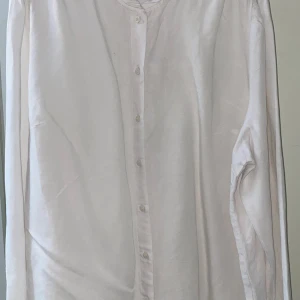 Vit långärmad linneskjorta från Kappahl  - Säljer en stilren vit långärmad skjorta från kappahl i luftigt linne. Skjortan har knappar framtill och en avslappnad passform med fina rynkade detaljer på ryggen. Perfekt för en fräsch och clean look. 