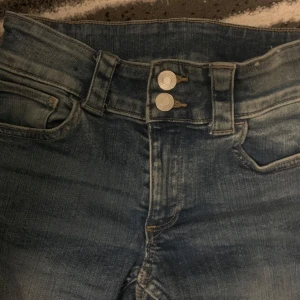 Low waist bootcut jeans med dubbla knappar - Snygga blå jeans med bootcut passform och dubbla knappar i midjan. Jeansen har fickor fram och bak. Köpta från hm storlek 164 cm.