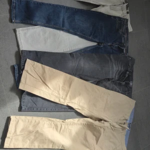 Mix av jeans och chinos, olika färger - Fyra par byxor: ett par mörkblå jeans från FSBN med kontrastsömmar, ett par ljusgrå jeans från Indicode Jeans, ett par svarta jeans från Denim Point och ett par beige chinos med klassisk passform. Perfekt för dig som vill variera stilen med både denim och chinos.