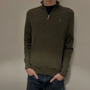 Morris Olivgrön stickad tröja med half zip - Olivgrön stickad tröja från Morris med half zip och liten broderad logga på bröstet. Tröjan har lång ärm, ribbade muddar och hög krage. Perfekt för lager-på-lager och snygg till jeans! Köpt på NK och endast använd 5-6 gånger, helt i dunder skick! Nypris 1800kr