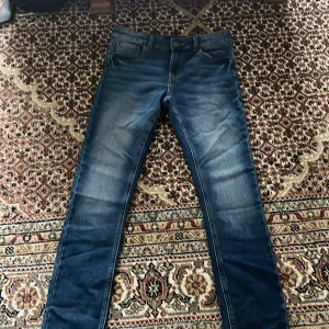 Blå skinny jeans från Kappahl 164 - Snygga blå skinny jeans från Kappahl i storlek 164. Jeansen har klassisk femficksdesign, normalhög midja och är tillverkade i stretchigt denim för en bekväm passform. Perfekta för dig som gillar en smal siluett och stilrena detaljer.