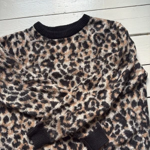 Leopardmönstrad stickad tröja Cubus - Säljer en stickad tröja från Cubus i storlek S med leopardmönster i svart, beige och bruna toner. Tröjan har rund halsringning och ribbade muddar vid hals, ärmslut och nederkant. Perfekt för dig som vill sticka ut med ett djurmönster.