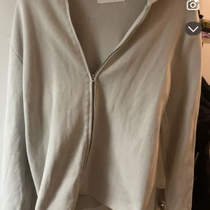 Beige hoodie med dragkedja från Samsøe Samsøe - Snygg beige hoodie från Samsøe Samsøe med hel dragkedja framtill och huva. Tröjan har en avslappnad passform och är tillverkad i mjukt material, perfekt för chill dagar. Långärmad och enkel att matcha med det mesta.