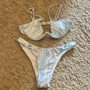 Blåvit bikini med vågigt mönster - Superfin bikini i en härlig blå och vit färg! Överdelen har bygel och smala axelband med spänne i ryggen. Båda delarna är i storlek XS🩵🤍