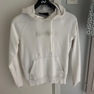 Hoodie  - Säljer min peakperfomance hoodie i vit med tryck på bröstet då den tyvärr blivit för liten. Inga tecken på slitage eller liknande. 