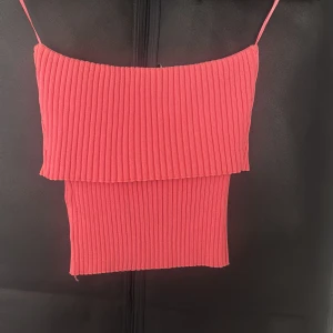 Ribbad rosa linnetopp i storlek S - Supersöt ribbad linnetopp i stark rosa färg med smala axelband. Toppen har en croppad passform och är tillverkad i ett stretchigt material som sitter snyggt på kroppen. Perfekt för varma dagar och att styla med jeans eller kjol.