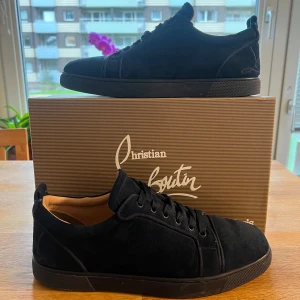 Mörkblåa Christian Louboutin - Snygga mörkblåa sneakers från Christian Louboutin i mjuk mocka med rund tå och snören som matchar skorna. Skorna har diskret broderad logga på hälen och den ikoniska röda sulan. Perfekta för dig som gillar stilrena och exklusiva sneakers med lyxig känsla.