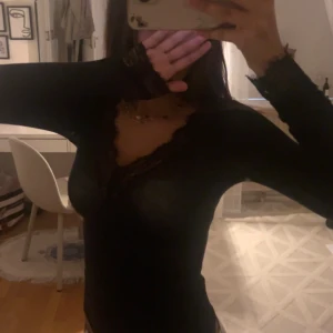 Intimissimi Svart Spetstopp  - Svart långärmad topp med djup v-ringning och snygga spetsdetaljer längs halsringningen. Den är i bra skick och helt felfri. Skriv jättegärna, skickar fler bilder på den!