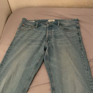 Ljusblå raka jeans från Jack &Jones - Snygga ljusblå jeans från Jack & Jones med klassisk femficksdesign och raka ben. Jeansen har en normal passform och är tillverkade i slitstarkt denim. Perfekta för en avslappnad och trendig look. STRL L