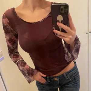 Vinröd Intimissimi topp med mönstrade ärmar - Vinröd topp med långa, utsvängda ärmar i transparent material. Från Intimissimi!