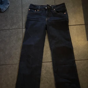 Mörkblå raka jeans med kontrastsömmar. Uppsyda för en person som är 158 cm. - Snygga mörkblå jeans med raka ben och klassiska kontrastsömmar. Jeansen har fem fickor, inklusive en bakficka med lock och knapp. Perfekta för dig som gillar en enkel och stilren look.