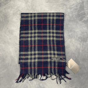 Burberry Halsduk - Skick: 7/10 (Vintage), begagnad, inga defekter. | Vad som ingår: Endast halsduken. | Ordinarie pris: +- 4000 SEK / 400 €. | ​​OBS: Halsdukarna finns i samma färgsättning men kan skilja sig något i modell eller detaljer, beroende på tillverkningsår eller kollektion