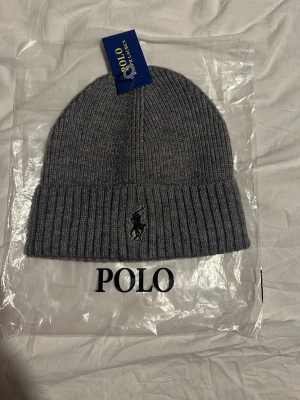 Ribbstickad ralph lauren mössa - En snygg grå ribbstckad ralph lauren mössa. Helt ny ingen har haft på den. En helt ny mössa i hemsidan kostar runt 800 kr. Accepterar bud som är runt mitt pris och rimliga. Jag kan även byta mot andra saker om ni erbjuder.Tveka inte att skriva om du har frågor!
