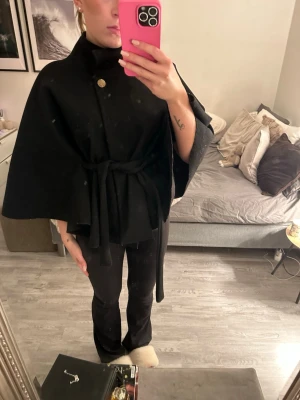 Svart ponchojacka med bälte och knapp - Säljer en svart poncho jacka från Missäy.  Den är i bra skick, inga synliga fel eller liknande.                                                      Skriv om du har några frågor💕