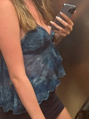 Topp  - Snygg blå linnetopp med  mönster och tunna axelband. Toppen är i ett lätt och transparent material med spetsdetaljer och v-ringning. Från Vinted så vet inte märke 🤷🏼‍♀️