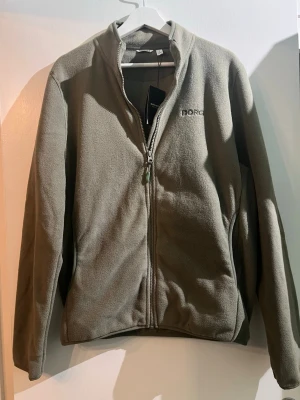 grön fleecejacka från Björn Borg - Säljer en olivgrön fleecejacka från Björn Borg med dragkedja framtill och diskret logga på bröstet. Jackan har hög krage och långa ärmar, perfekt för kyliga dagar. Enkel och stilren design som funkar till det mesta. Helt ny! Aldrig andvänd!