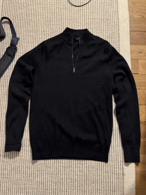 Mörkblå half zip polotröja - Klassisk svart polotröja från mango med half zip-dragkedja framtill. Tröjan är långärmad och har en stilren, minimalistisk look som passar perfekt till både jeans och kostymbyxor. Tillverkad i mjuk ull för extra komfort. Storlek medium men sitter som small
