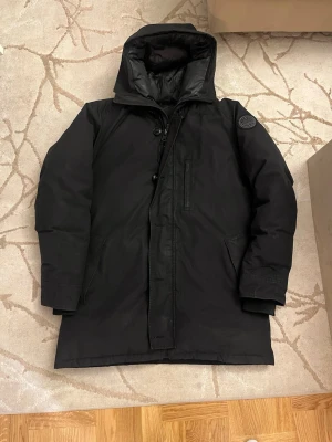 Svart dunjacka från Canada Goose - Säljer en svart, lång dunjacka från Canada Goose med pels 