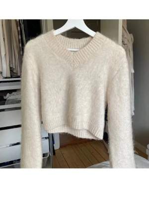 Mohair/Wool stickad tröja❤️ - Supermjuk och fluffig beige stickad tröja med croppad passform och v-ringad hals. Långa ärmar och bred ribbad kant vid hals, ärmslut och nederkant. Perfekt för lager-på-lager under hösten och vintern.